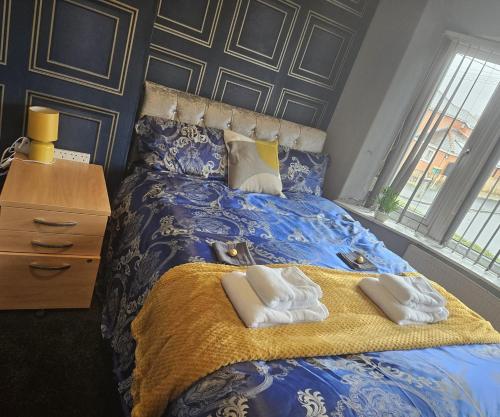 a bedroom with a blue bed with towels on it at Aldwych house, For Holidays, Contractors & Relocation, Free Parking & Wi-Fi in Preston