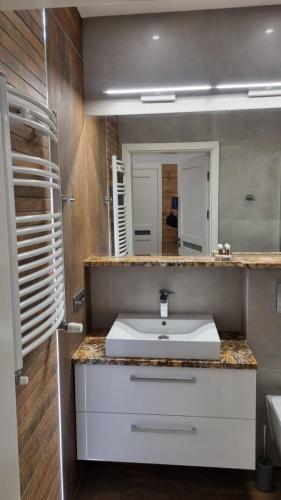 a bathroom with a white sink and a mirror at Apartament BRYZA in Pobierowo
