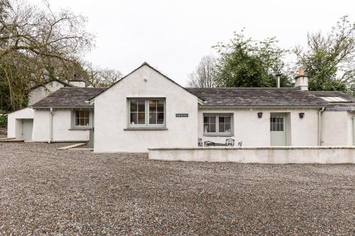 ein weißes Haus auf einer Kieseinfahrt in der Unterkunft The Bothy in Ulverston