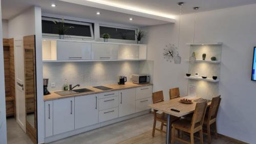 a kitchen with white cabinets and a wooden table at Apartament BRYZA in Pobierowo