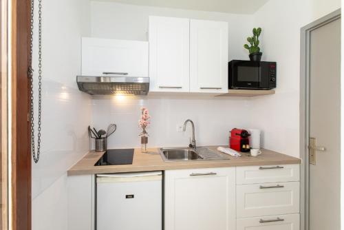 eine Küche mit weißen Schränken und einer Spüle in der Unterkunft Nouveau - Le CityScape - Petite Venise in Colmar