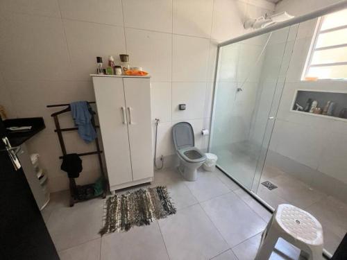 uma casa de banho branca com um WC e um chuveiro em Casa grande no Guarau em Peruíbe