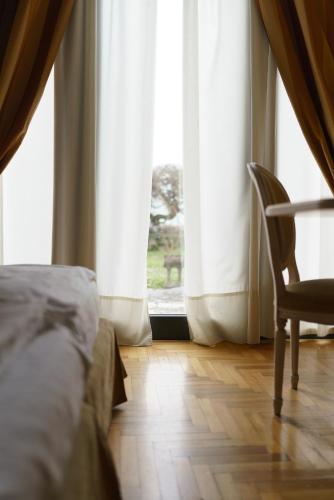 a bedroom with a bed and a chair and a window at Hotel Villa Policreti in Castello dʼAviano