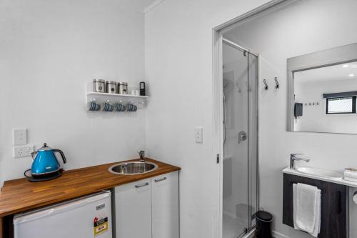 La petite salle de bains est pourvue d'un lavabo et d'une douche. dans l'établissement Joy's Rest Cabin - Whangamata, à Whangamata