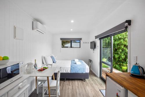 a bedroom with a bed and a table in a kitchen at Joy's Rest Cabin - Whangamata in Whangamata