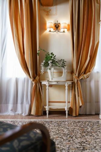a potted plant on a table in a room with curtains at Hotel Villa Policreti in Castello dʼAviano