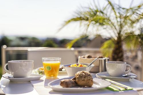 a table with plates of food and cups of orange juice at Taome Feng Shui Stadthotel Breisgau in Emmendingen