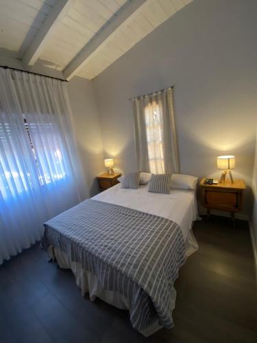 sypialnia z białym łóżkiem, 2 stolikami nocnymi i 2 oknami w obiekcie Casa Colonial en frente a la plaza w mieście Cafayate