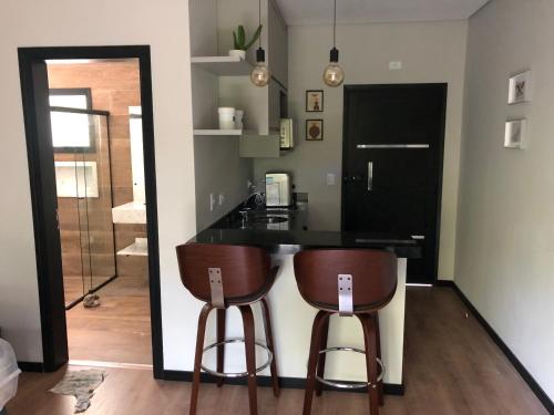 a kitchen with a counter and two bar stools at La Floresta Suites in Campos do Jordão