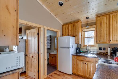 a kitchen with wooden cabinets and a white refrigerator at Cozy Ouray Hideaway Mountain Views, Steps to Main in Ouray