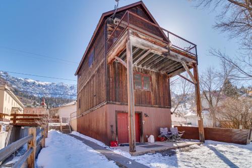 a wooden building with a red door in the snow at Cozy Ouray Hideaway Mountain Views, Steps to Main in Ouray