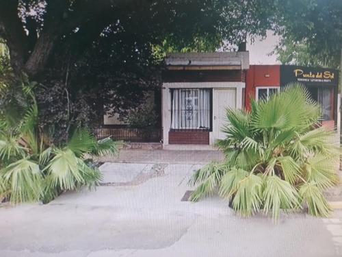 un pequeño edificio con una puerta y algunas palmeras en Mistela Altos de Mendoza- Con Wifi- Con Servicio Gratuito al Aeropuerto o la Terminal- en Godoy Cruz