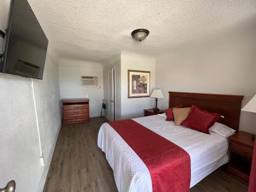 a bedroom with a large bed with red pillows at Arizona 9 Motor Hotel in Williams