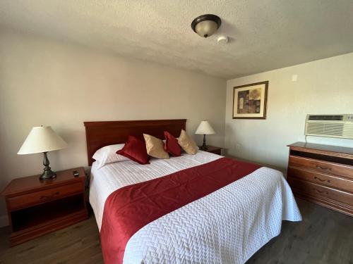 a bedroom with a large bed with red pillows at Arizona 9 Motor Hotel in Williams