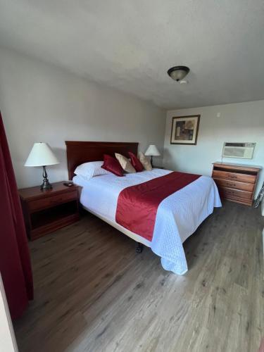 a bedroom with a large bed with a red and white blanket at Arizona 9 Motor Hotel in Williams
