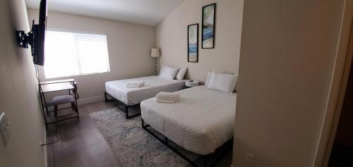 a small bedroom with two beds and a window at Oceanside Beach style King & 2 queen beds in Oceanside
