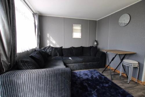a living room with a black couch and a table at Beautiful Chalet close to the beach in Eastchurch