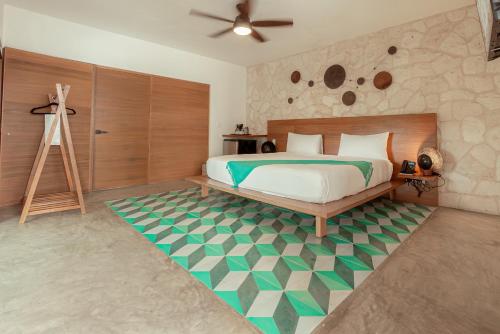 a bedroom with a bed with a green and white rug at Prana Boutique Hotel Tulum in Tulum