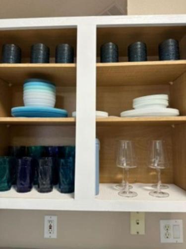 a white cabinet with glasses and plates and dishes at Last Mango in Palm Coast in Palm Coast