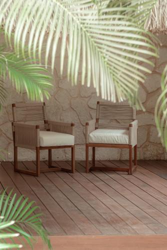 two chairs and a bench in front of a wall at Prana Boutique Hotel Tulum in Tulum