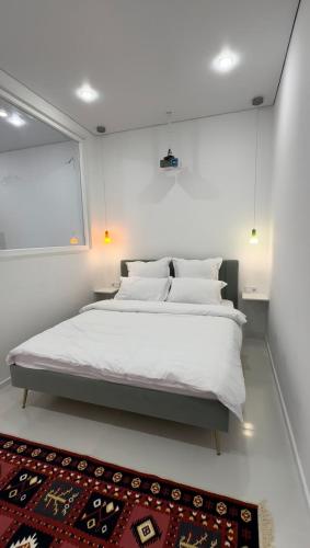 a bedroom with a large white bed and a rug at Идеальный домик для отдыха in Almaty