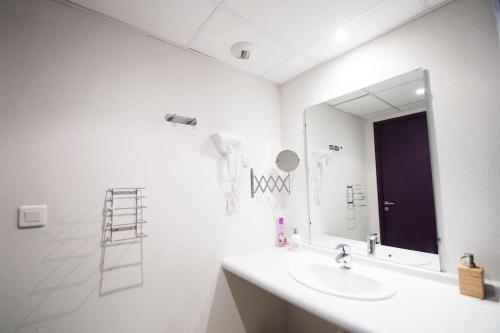 une salle de bain blanche avec un lavabo et un miroir dans l'établissement Studio Au Sommet - clim - gare, à Lourdes