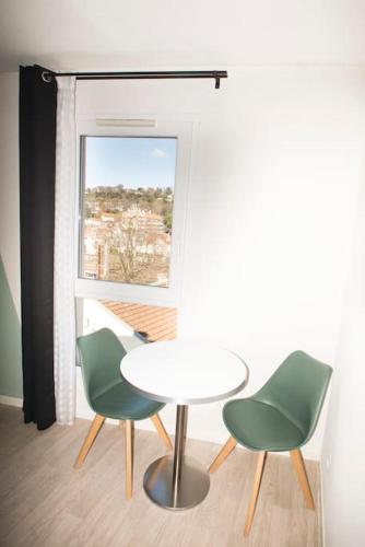 une table et deux chaises dans une pièce avec une fenêtre dans l'établissement Studio Au Sommet - clim - gare, à Lourdes