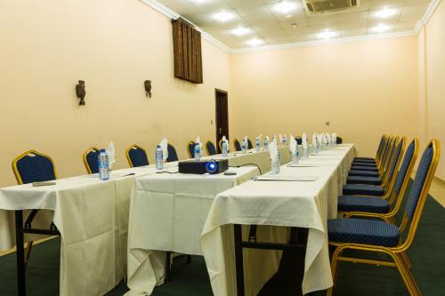 a row of tables in a room with blue chairs at Midindi Hotel in Accra