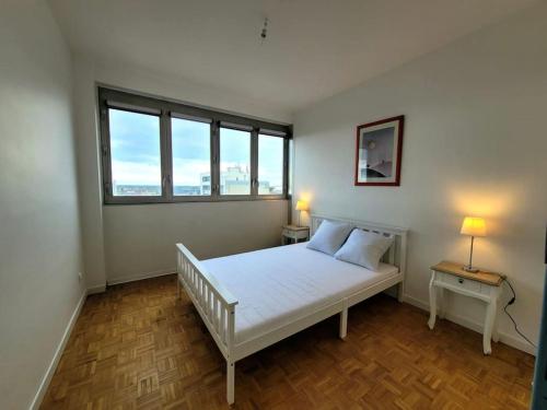 - une chambre avec un lit blanc et 2 fenêtres dans l'établissement La Case à Jeannette, à Châteauroux