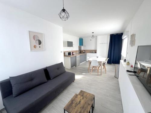 un salon avec un canapé noir et une table dans l'établissement 178B - Appartement T2 Tout Confort - Wifi Netflix, à Le Gond-Pontouvre