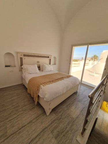 a bedroom with a large bed and a large window at Musk de djerba suite aziz avec piscine in Temlale