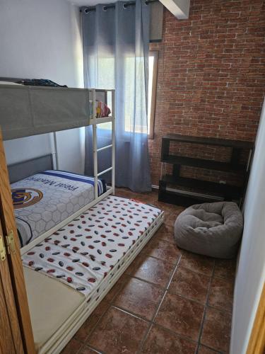 - une chambre avec des lits superposés et un mur en briques dans l'établissement La Casona de Simón, un pequeño paraíso urbano, à Camarma de Esteruelas