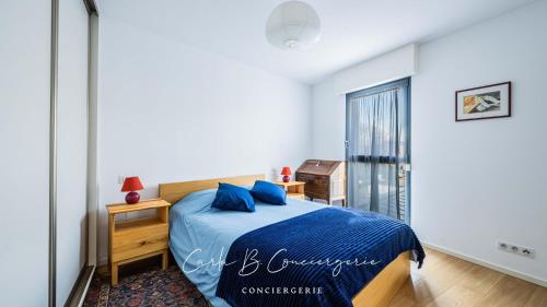 une chambre avec un lit avec des draps bleus et une fenêtre dans l'établissement ROSEMARINE - APPARTEMENT CONCARNEAU VUE MER 2 adultes/2enfants, à Concarneau