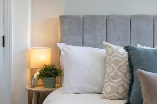 a bed with white pillows and a gray headboard at Elland Retreat By NordStay in Beeston Hill