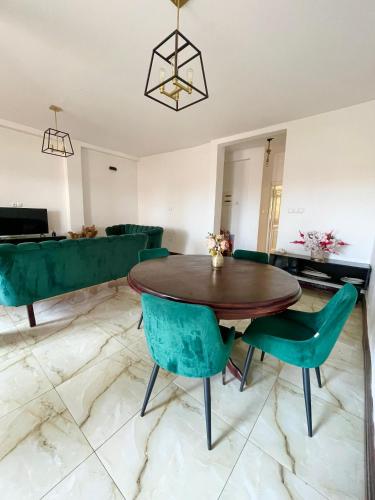 a living room with a wooden table and green chairs at White Palm Residence in Yaoundé