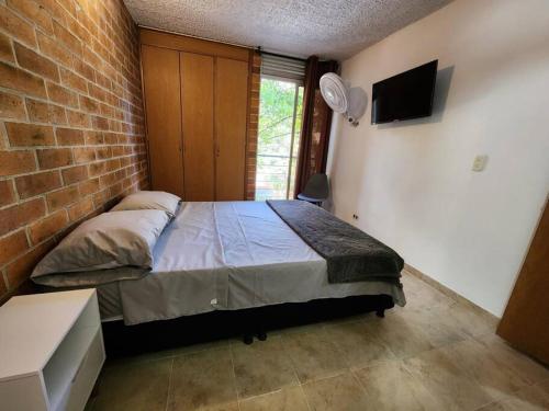 um quarto com uma cama e uma parede de tijolos em aparta estudio cerca a C.C em Ibagué