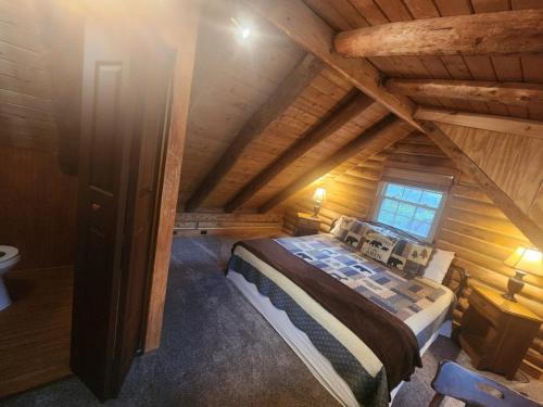 a attic bedroom with a bed in a wooden house at VERY private, real log cabin with hot tub! in Sevierville