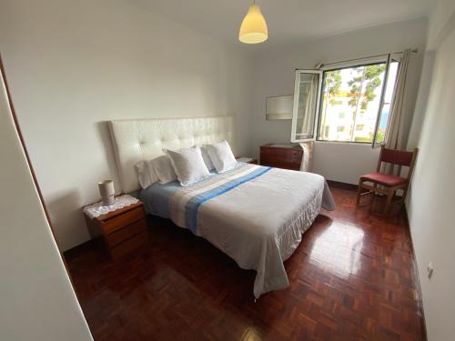 a bedroom with a white bed and a window at Inmaculado Apartment in Funchal