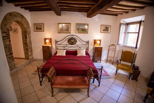 een slaapkamer met een bed en 2 stoelen. bij Casa degli Archi Bibbona alta in Bibbona