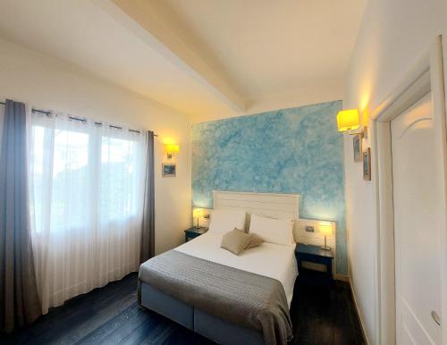a bedroom with a white bed and a blue wall at Hotel La Villa Del Mare in Cagliari