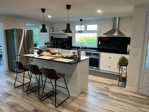 a kitchen with a large island with bar stools at Newly Renovated villa with magnificent views in Coaticook