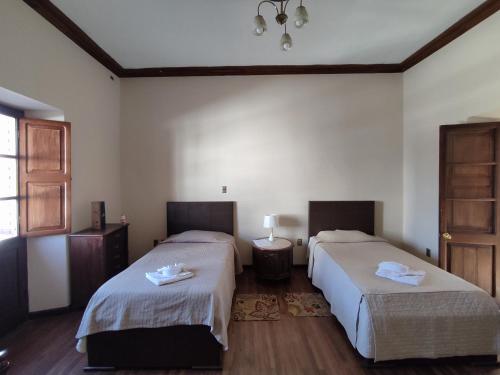 a room with two beds and a window at La Culta hostal & centro cultural in Sucre