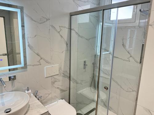 a bathroom with a shower and a toilet and a sink at Ionian View B&B in Himare