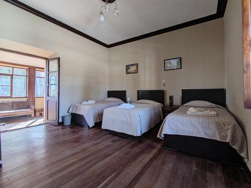 two beds in a room with wooden floors at La Culta hostal & centro cultural in Sucre