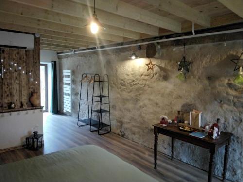 a room with a bed and a table and a wall at Chambres d'hôtes Les cabris in Verneix