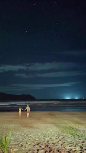 a man and a dog standing on a beach at night at 8 Star Paradise in Locaroc