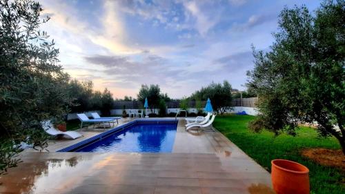 a backyard with a swimming pool with chairs and a table at Maison d'hôtes La Ferme AZIZA in Fez