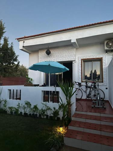 a house with a blue umbrella in front of it at Maison d'hôtes La Ferme AZIZA in Fès
