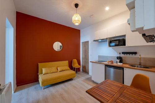 sala de estar con sofá amarillo y cocina en Les Maisons Acajou - Valenciennes, en Valenciennes