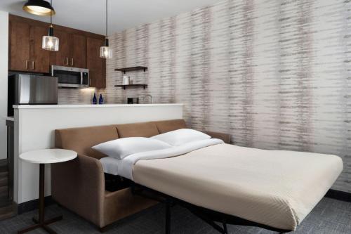 a bedroom with a bed and a couch and a kitchen at Inn at Bellefield Residence Inn by Marriott in Hyde Park